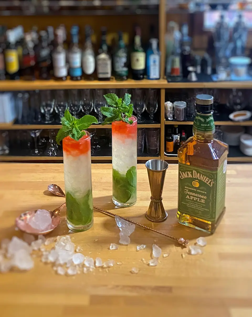 Two Apple Julep cocktails next to a bottle of Jack Daniel's and crushed ice